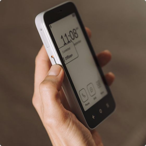 Person holding a smartphone with monochrome display showing time and offline status.